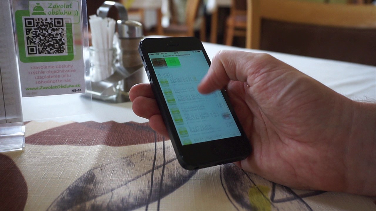 Smartf&oacute;n v ruke hosťa zobrazuj&uacute;ci zoznam &scaron;al&aacute;tov v mobile &mdash; Ceasar &scaron;al&aacute;t, Kapustov&yacute; &scaron;al&aacute;t, Mie&scaron;an&yacute; &scaron;al&aacute;t, &Scaron;al&aacute;t Al Tonno s cenami a alerg&eacute;nmi